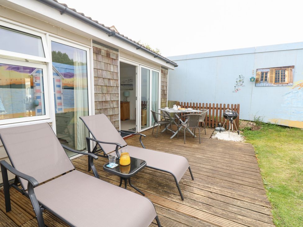 An outdoor patio with sun loungers and a table at Plimoth N8 Yarmouth