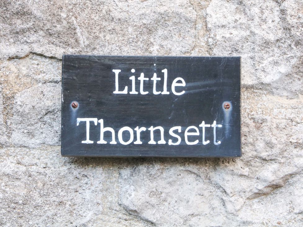 A sign displaying 'Little Thornsett' on a stone wall