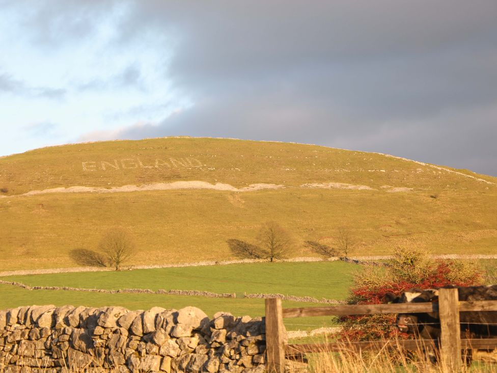 A hill with the word ENGLAND carved into it and a stone wall in the foreground at Little Thornsett