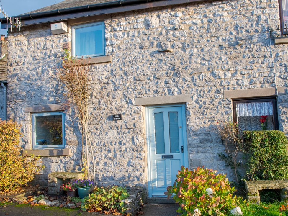 A stone cottage with a blue front door and plants at Little Thornsett