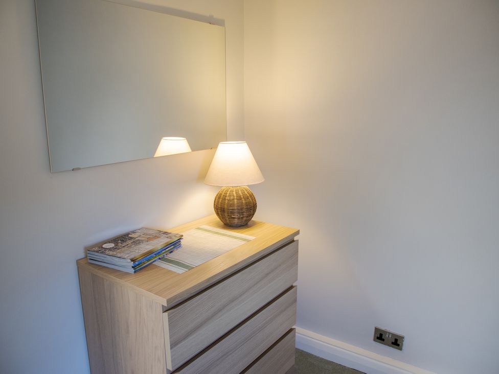 A bedroom with a drawer unit, lamp, and mirror at Little Thornsett in Chelmorton