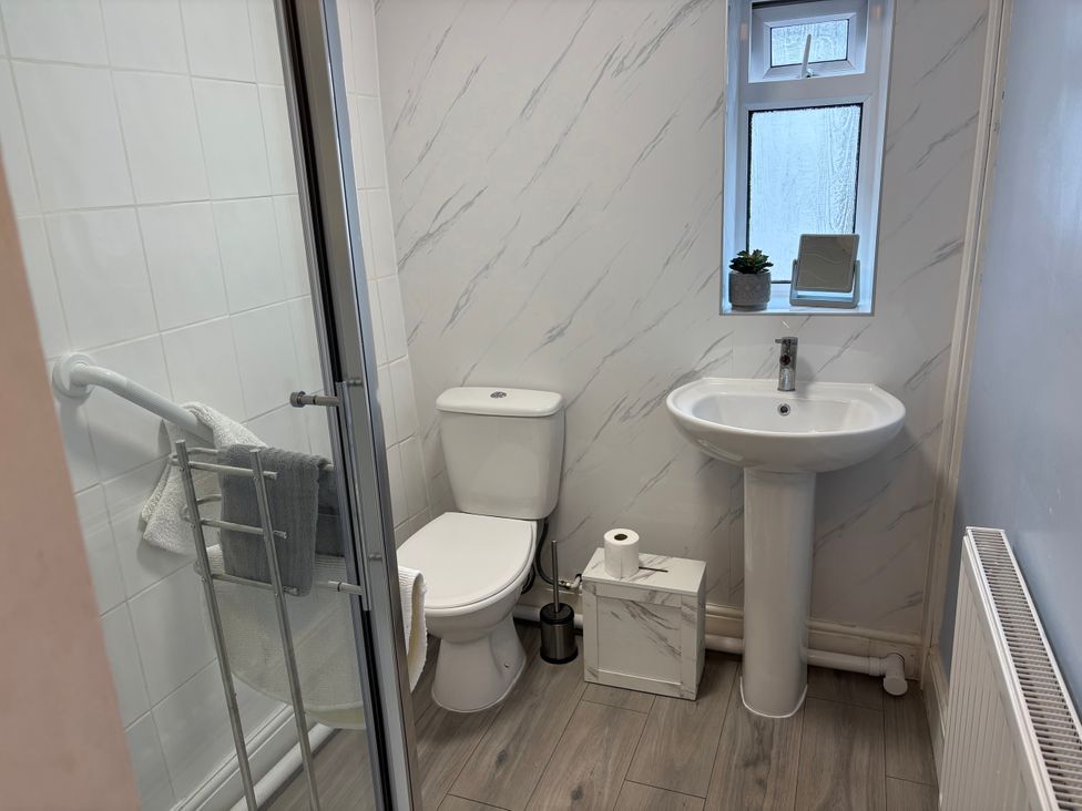 A bathroom featuring a shower, toilet, sink, and towel rack at Coedmor in Newport, Pembrokeshire