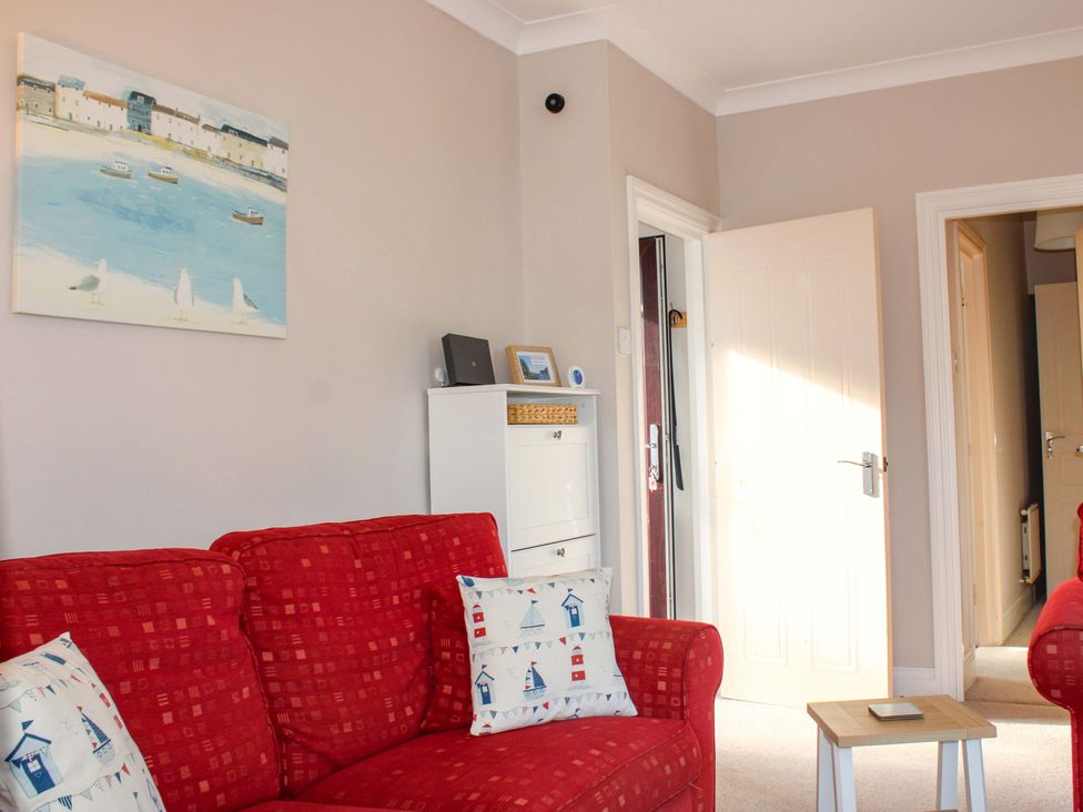 A living room with a red sofa and painting at 2 The Elms in Salcombe