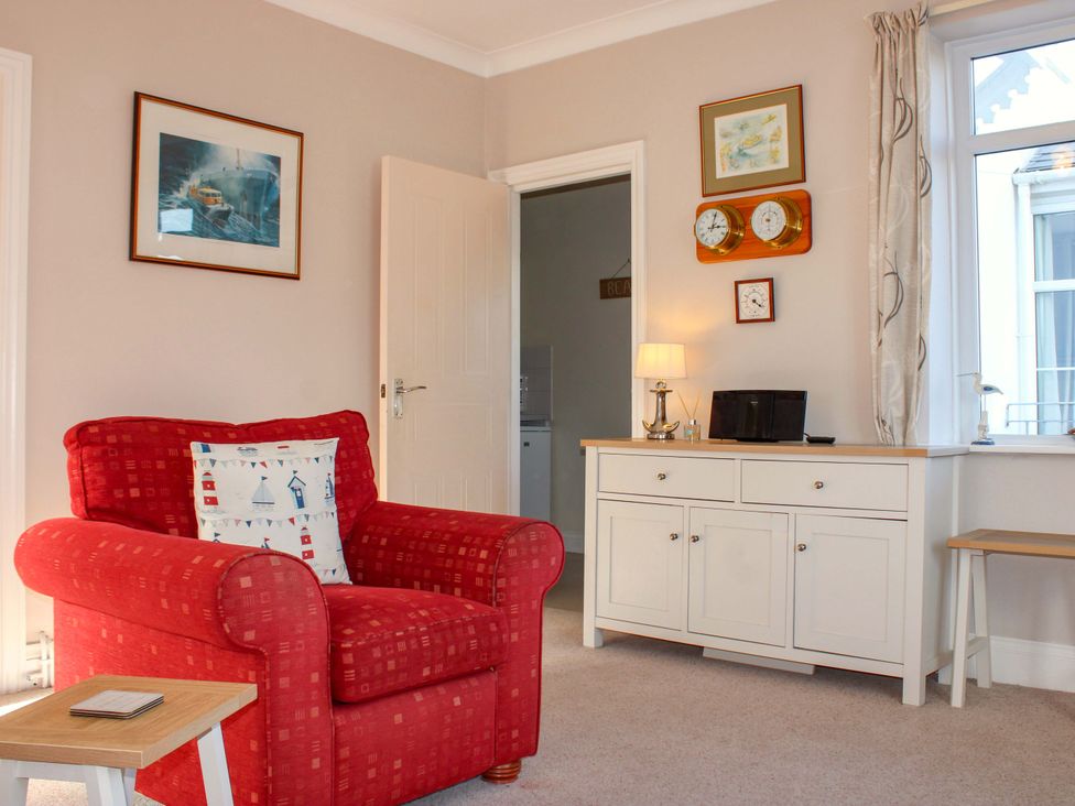 A living room with an armchair and console table at 2 The Elms Salcombe
