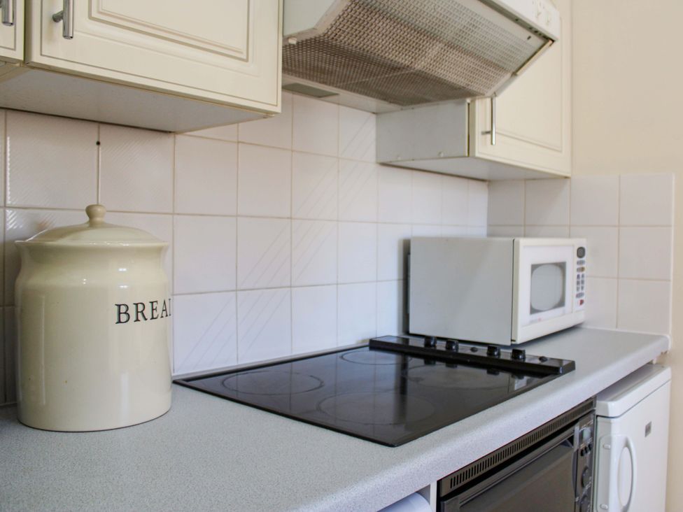 A kitchen with a cooker, microwave, and storage jar at 2 The Elms, Salcombe