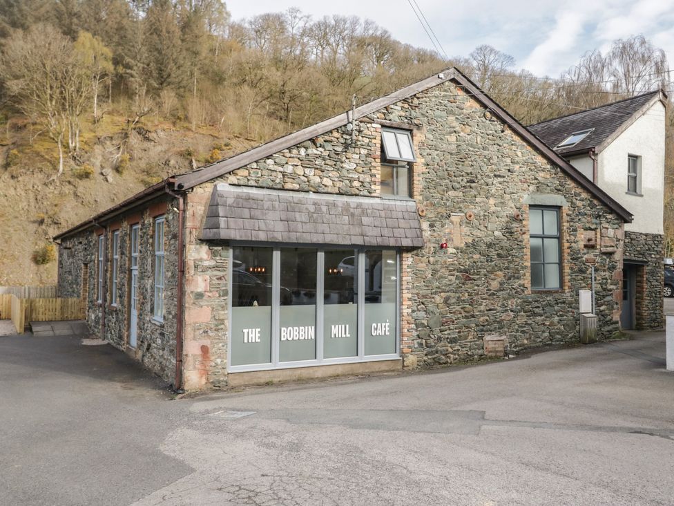 A stone building with large windows and signage at The Bobbin Mill Café in Keswick