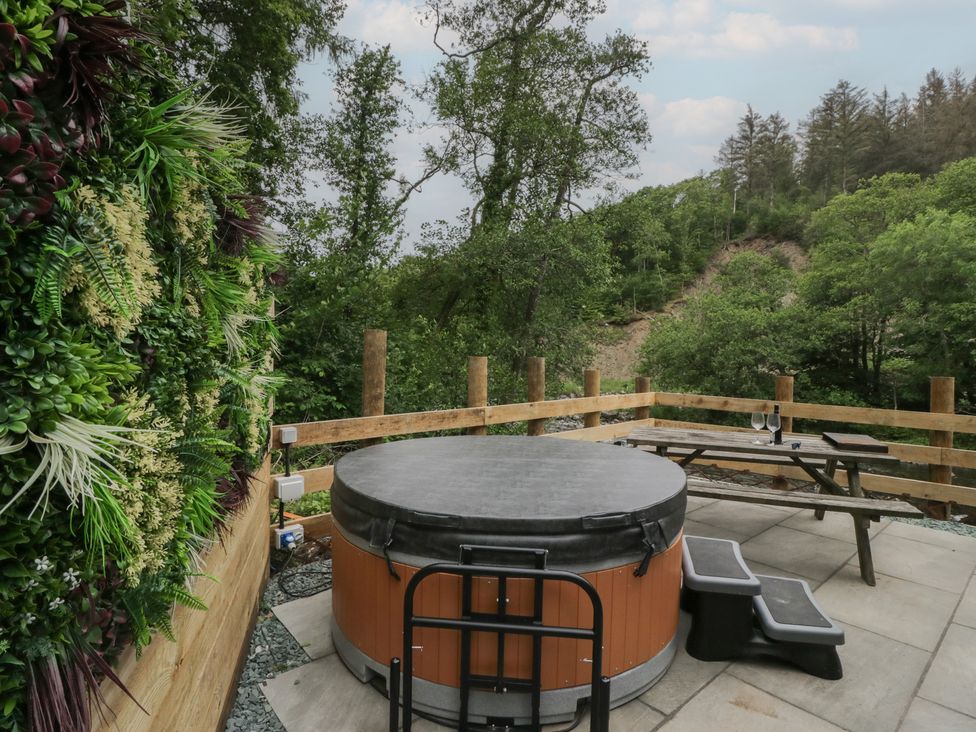 An outdoor space with a hot tub and a wooden table at Dubs Luxury Family Pod in Keswick