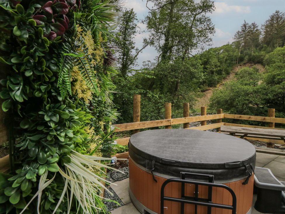 An outdoor area with a hot tub and artificial plants at Dubs Luxury Family Pod in Keswick