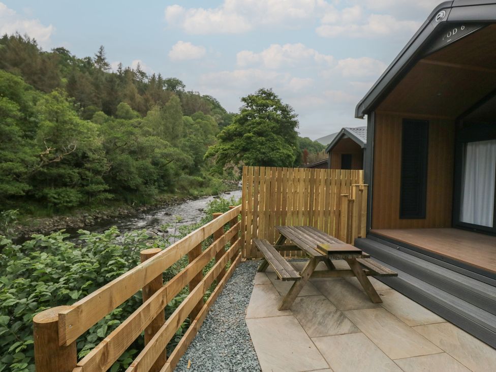 An outdoor area with a table and bench near a river at Lingy Luxury Family Pod in Keswick