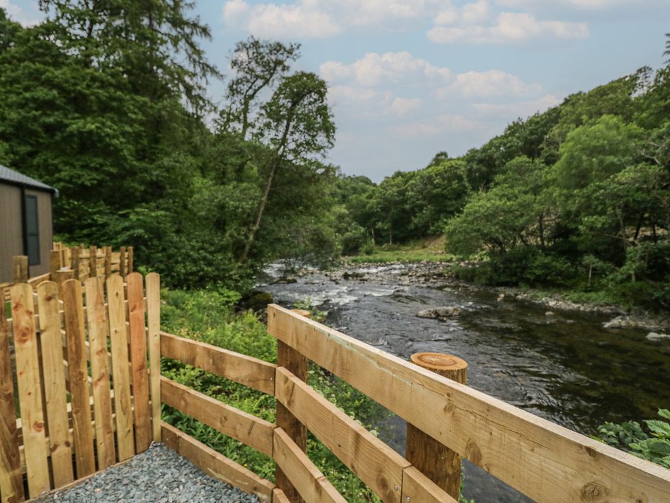 A river surrounded by trees and a wooden fence at Lingy Luxury Family Pod in Keswick