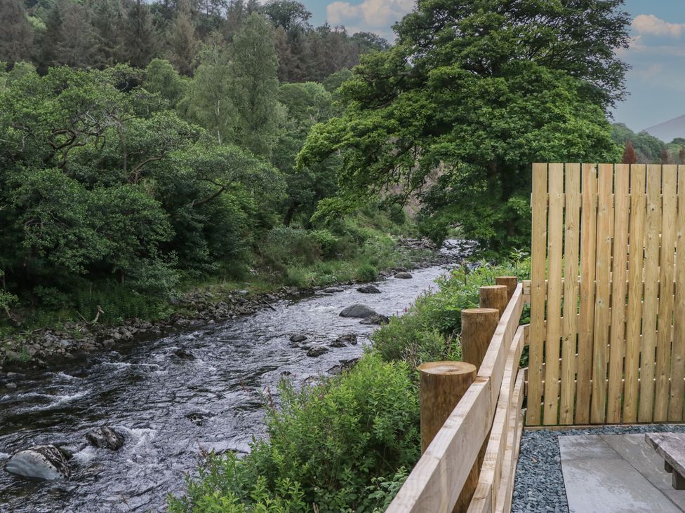 A view of a river with rocks and greenery at Sail Luxury Family Pod Keswick