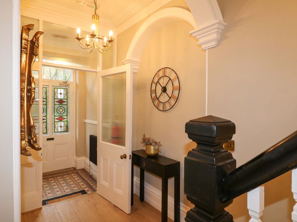 A hallway with a stained glass door and a wall clock at High Peaks Villa in Buxton