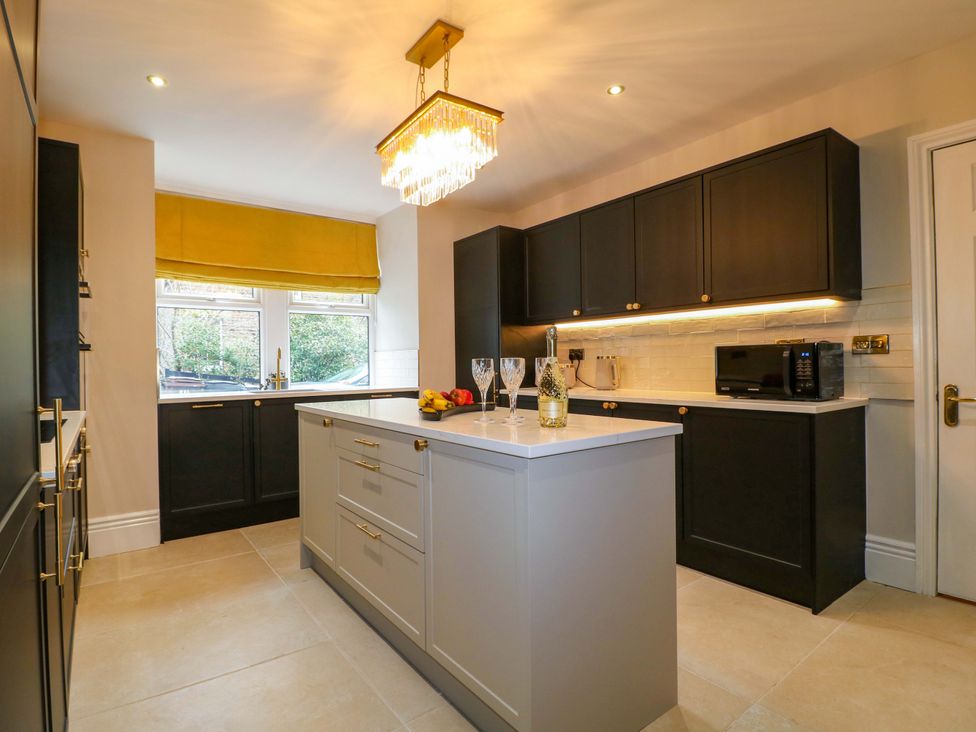 A kitchen with an island, cabinets and a window at High Peaks Villa in Buxton
