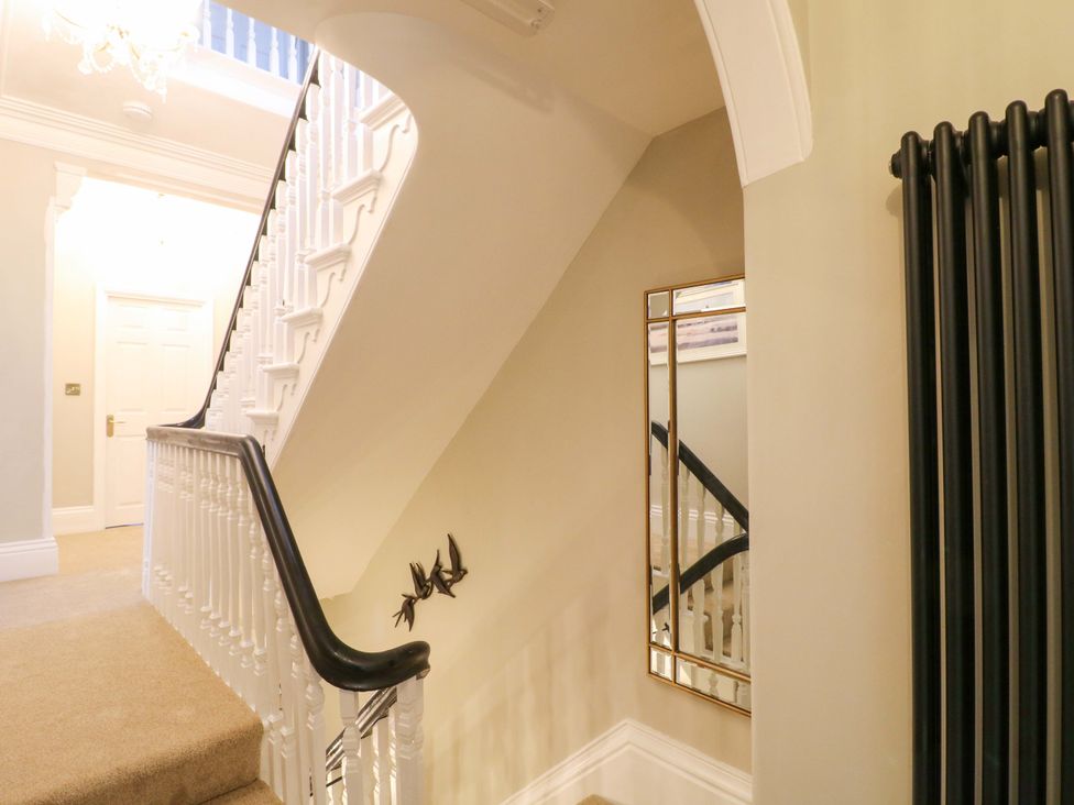 A hallway with a staircase and mirror at High Peaks Villa in Buxton