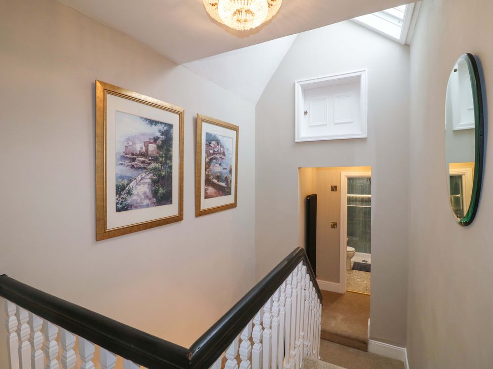 A hallway with framed pictures and a door leading to a bathroom at High Peaks Villa in Buxton