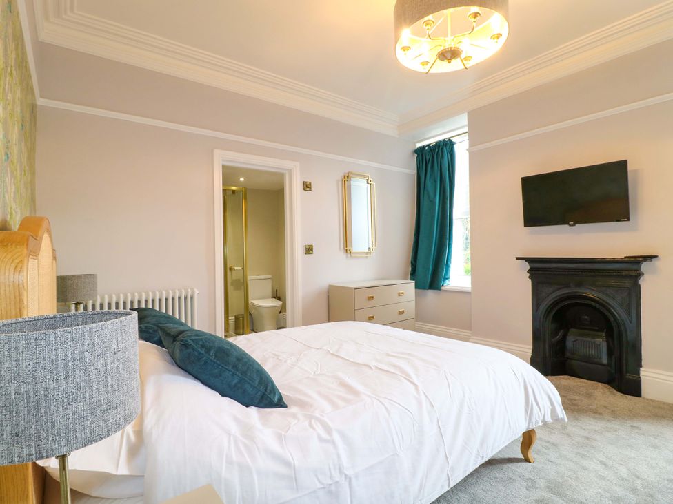 A bedroom with a bed and television at High Peaks Villa in Buxton
