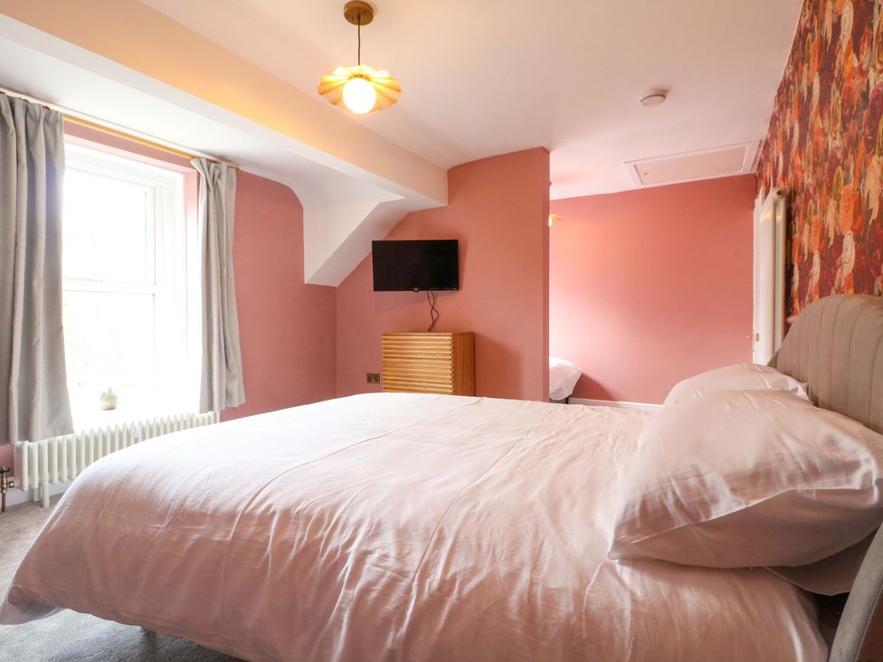 A bedroom with a bed and television at High Peaks Villa in Buxton