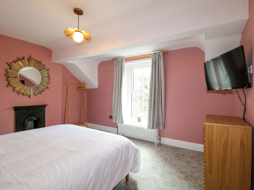 A bedroom with a bed and television at High Peaks Villa in Buxton