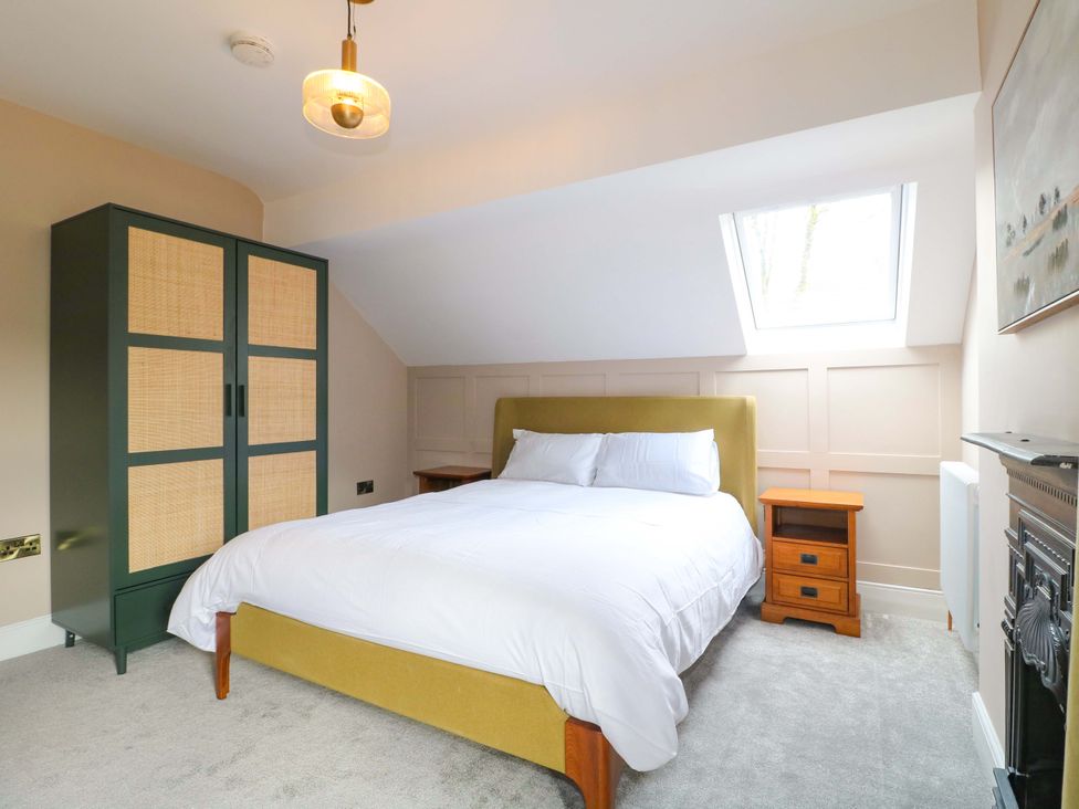 A bedroom with a bed, wardrobe, nightstand and window at High Peaks Villa in Buxton