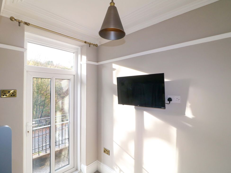A room with a TV on the wall and a door in High Peaks Villa Buxton