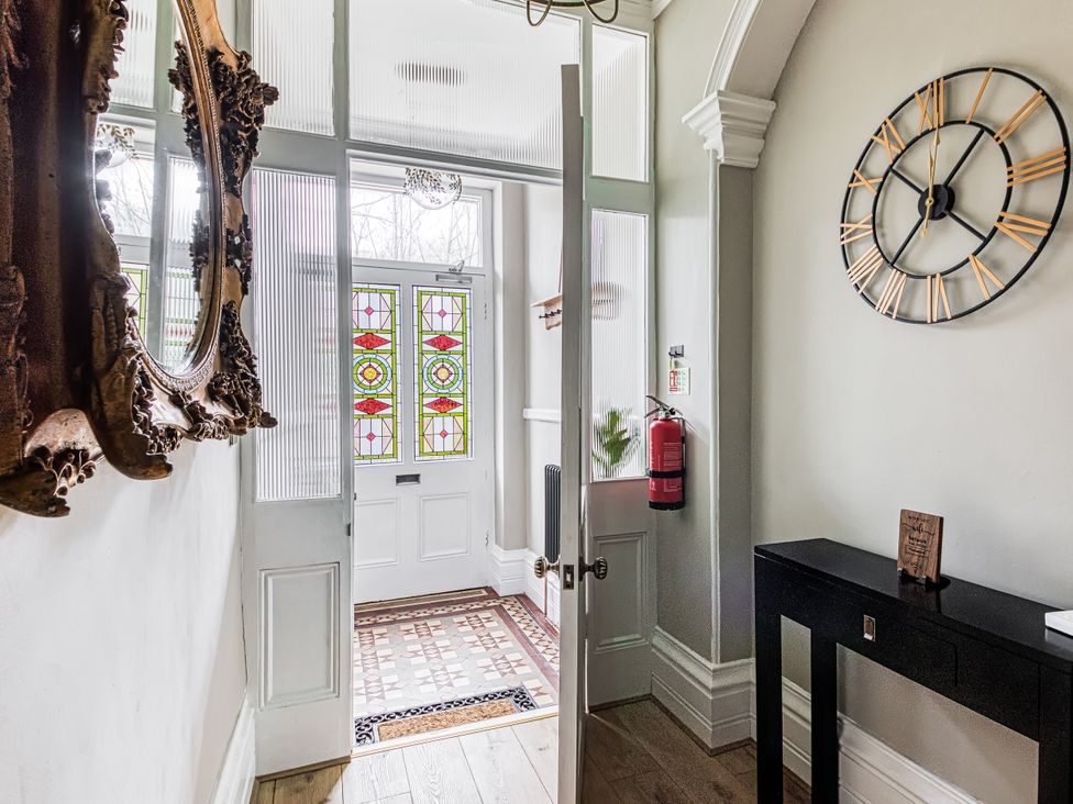 A hallway with a mirror and stained glass door at High Peaks Villa in Buxton