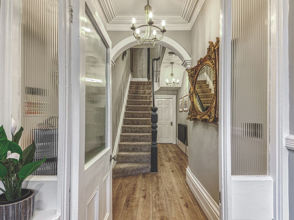 A staircase and chandelier in the hallway at High Peaks Villa Buxton