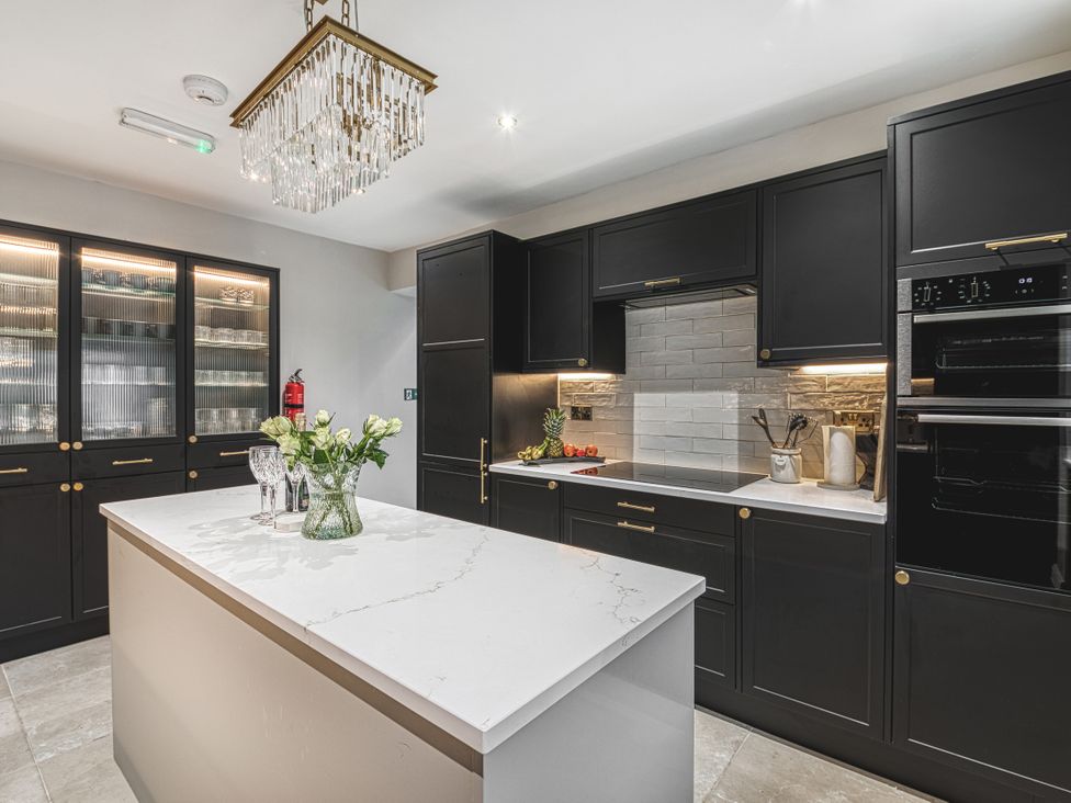 A kitchen with cabinets and an island at High Peaks Villa Buxton