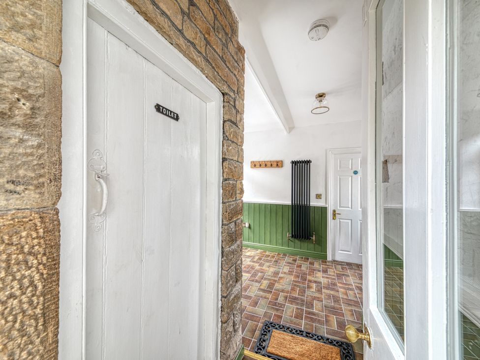 A hallway with a toilet door and coat hooks at High Peaks Villa Buxton