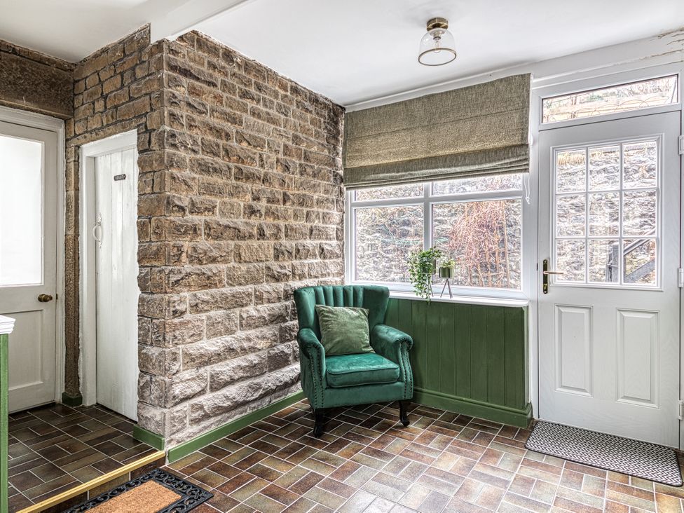 A hallway with a green chair and windows at High Peaks Villa Buxton