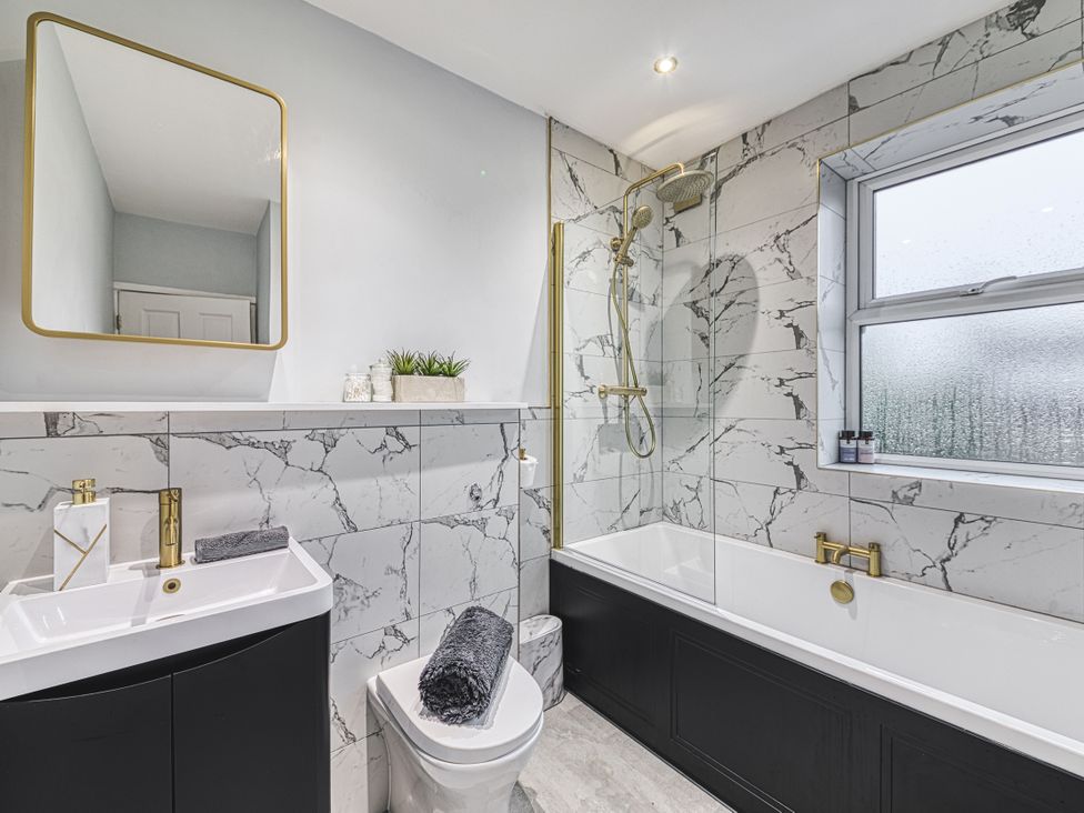 A bathroom with a bathtub, shower, and sink at High Peaks Villa in Buxton