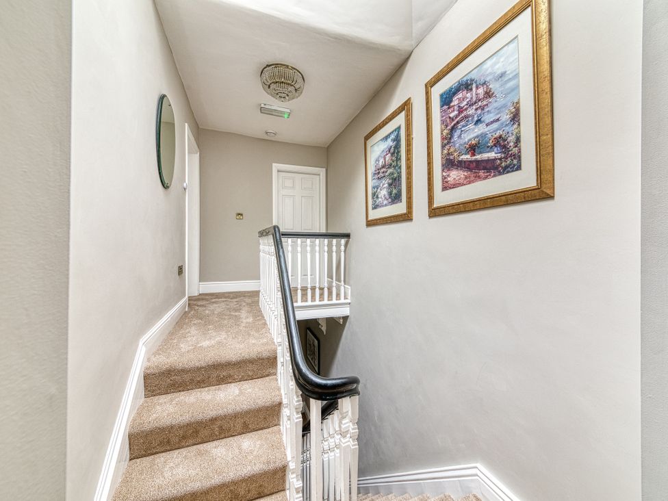 A hallway with a staircase and paintings at High Peaks Villa in Buxton