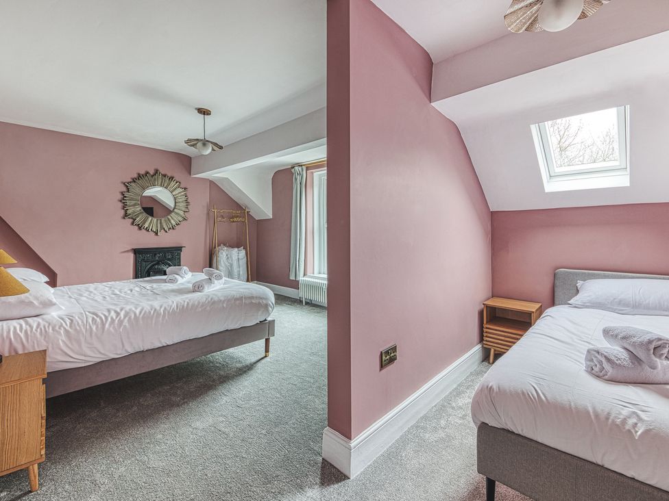 A bedroom with two beds and a mirror at High Peaks Villa in Buxton