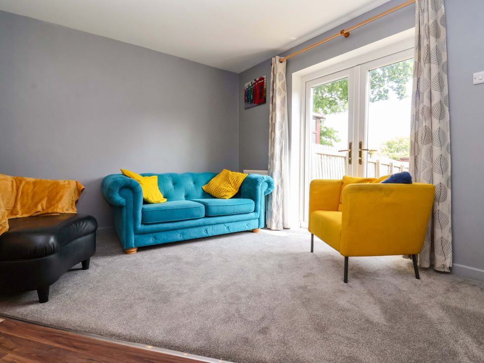 A living room with a blue sofa and yellow armchair at 8 Wharfedale Mews in Otley
