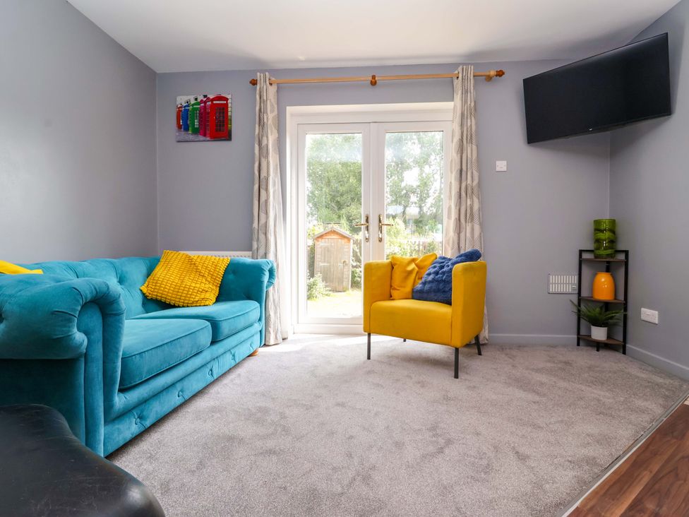 A living room with a blue sofa and yellow chair at 8 Wharfedale Mews in Otley