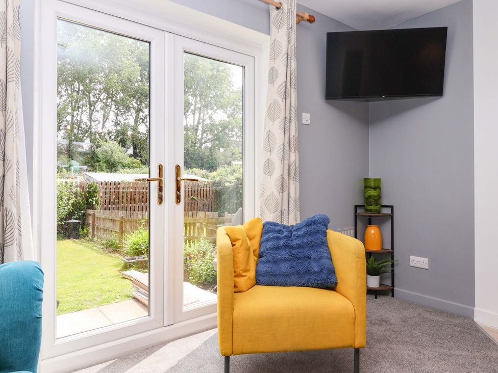 A living room with a yellow armchair and a television at 8 Wharfedale Mews in Otley