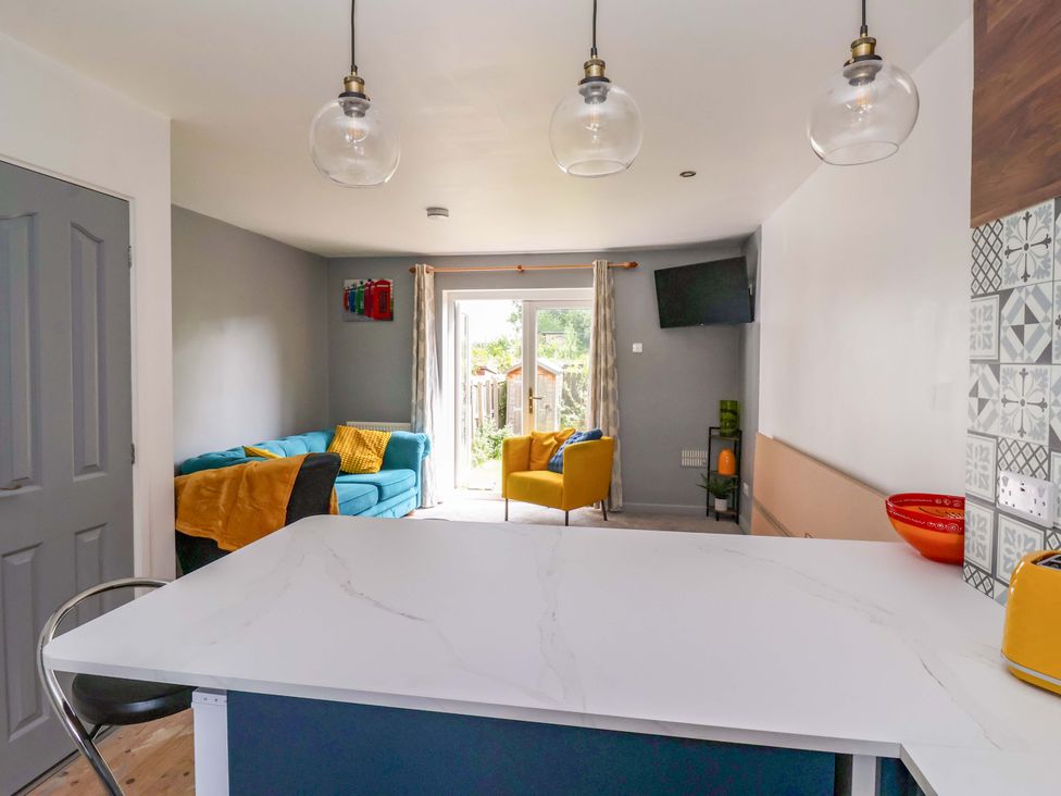 A kitchen with a table and chairs overlooking a living area at 8 Wharfedale Mews in Otley