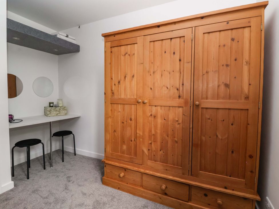 A bedroom with a wardrobe and a table with stools at 8 Wharfedale Mews in Otley