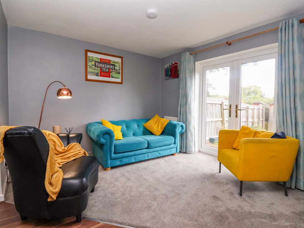 A living room with a blue sofa and yellow armchair at 8 Wharfedale Mews in Otley