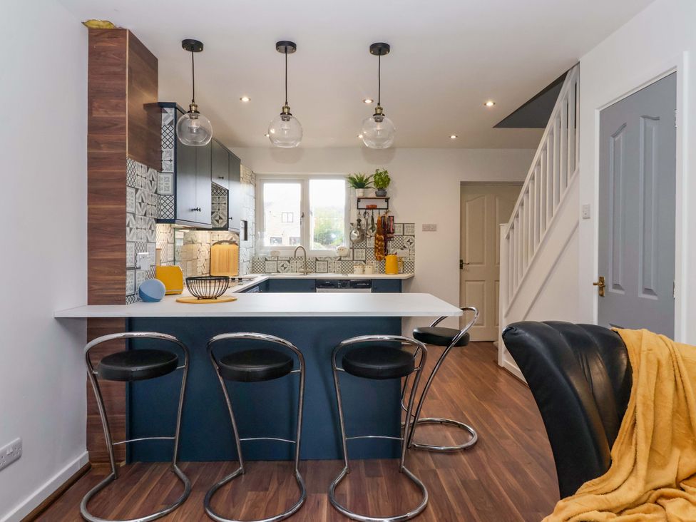 A kitchen with an island, stools, and cabinets at 8 Wharfedale Mews in Otley
