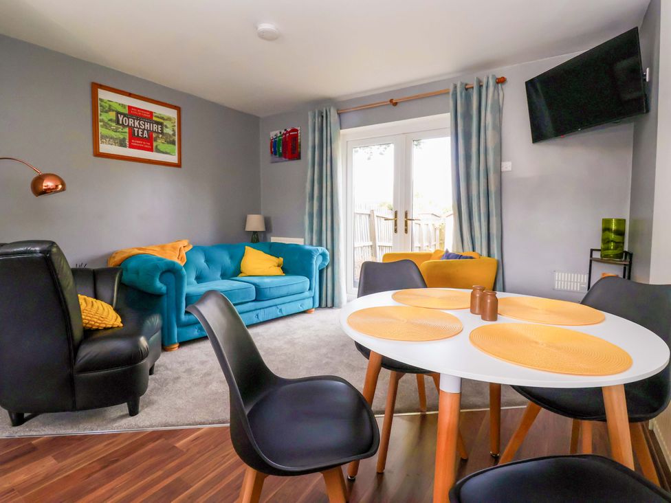 A living room with a sofa and dining table at 8 Wharfedale Mews in Otley