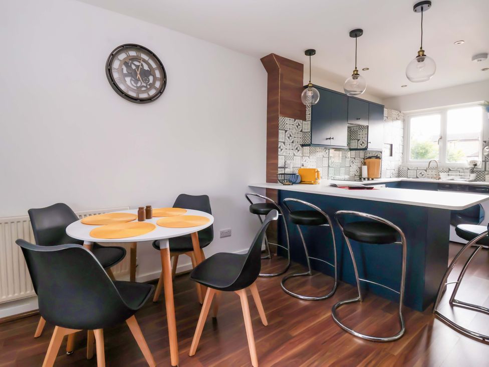 A kitchen with a dining table and bar stools at 8 Wharfedale Mews Otley
