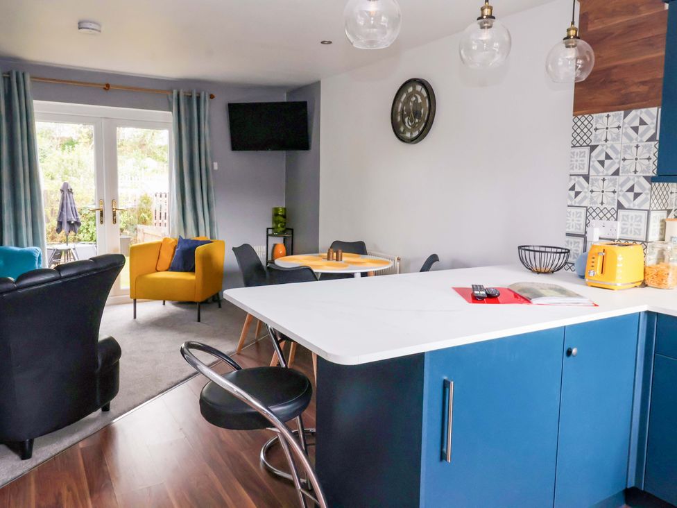 A living room with a sofa and dining area at 8 Wharfedale Mews in Otley