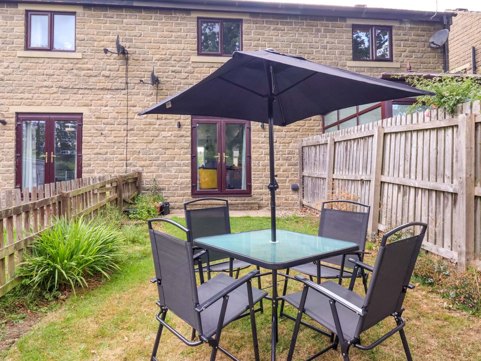 A garden with table and chairs under an umbrella at 8 Wharfedale Mews Otley