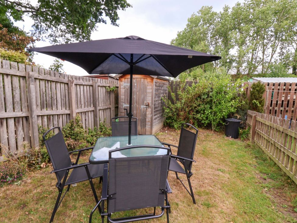 A garden with a table and chairs under an umbrella at 8 Wharfedale Mews in Otley