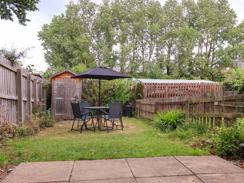 A garden with a table and chairs under an umbrella at 8 Wharfedale Mews Otley
