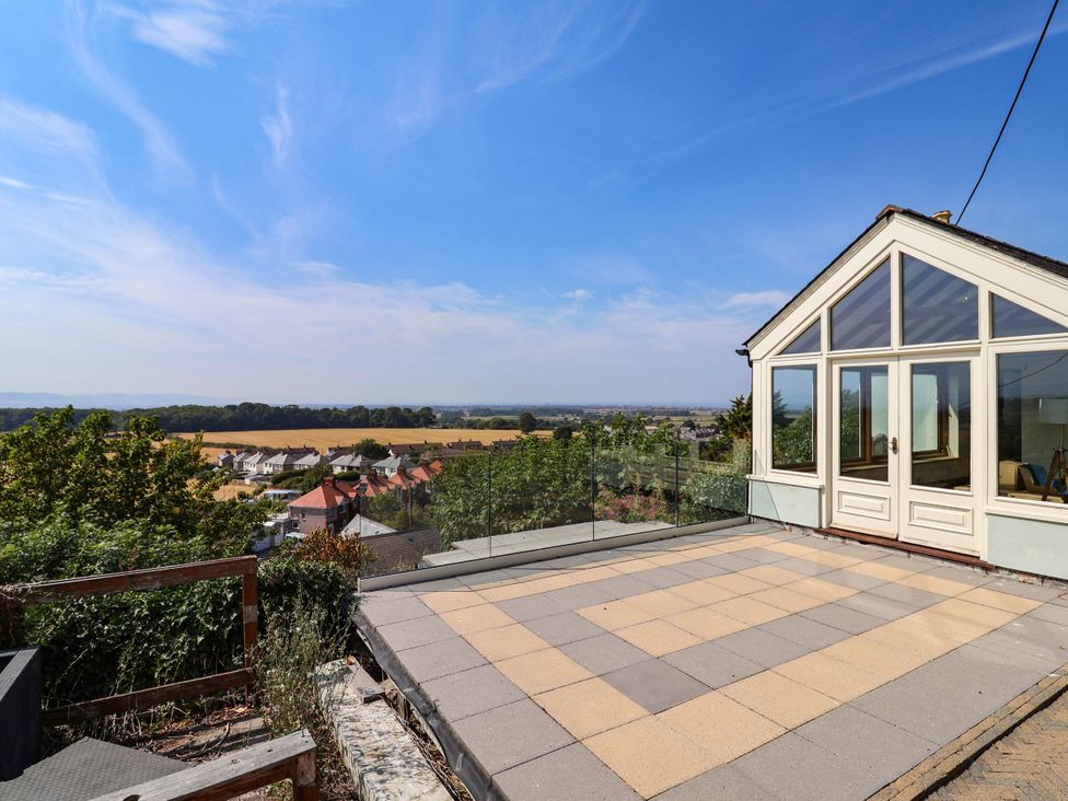 An outdoor area with a glass railing overlooking a landscape at Ael Y Bryn Dyserth