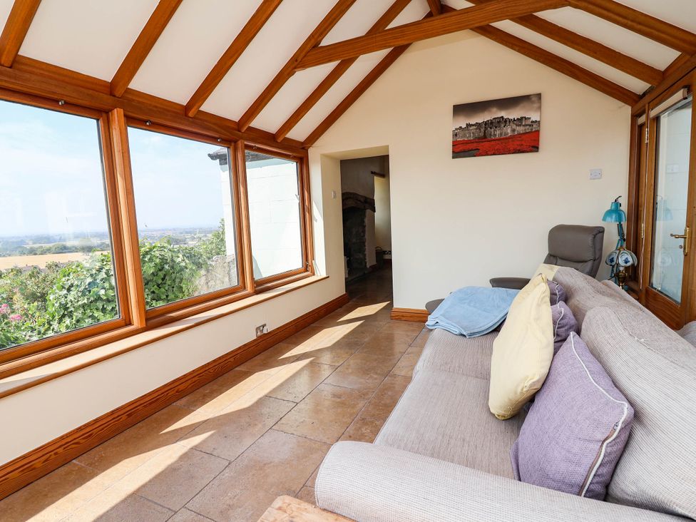 A conservatory with windows and a sofa at Ael Y Bryn Dyserth
