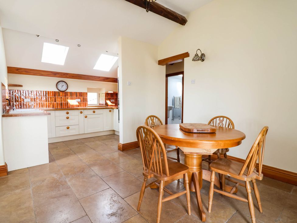 A dining room with a round table and chairs at Ael Y Bryn in Dyserth