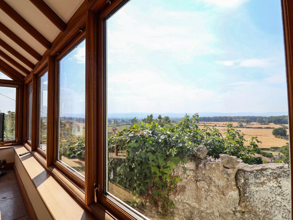 A conservatory with large windows overlooking a landscape at Ael Y Bryn in Dyserth