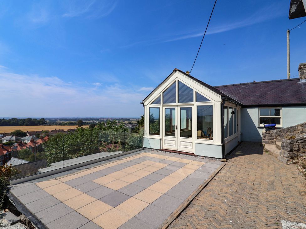 A conservatory with glass doors and a patio at Ael Y Bryn in Dyserth